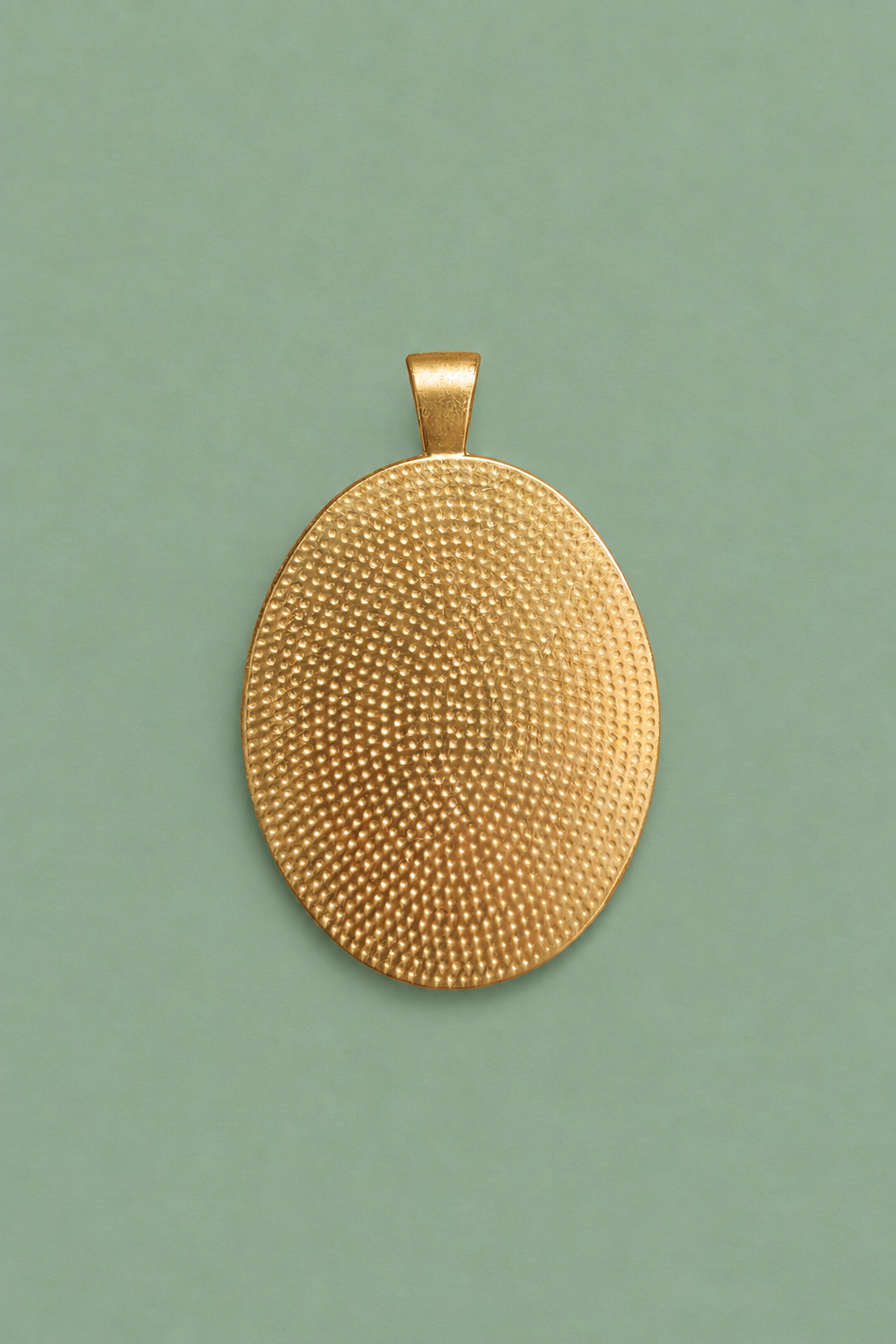 Back view of the oval Edgar Degas medallion showing the textured antique brass setting on a muted sage green background.