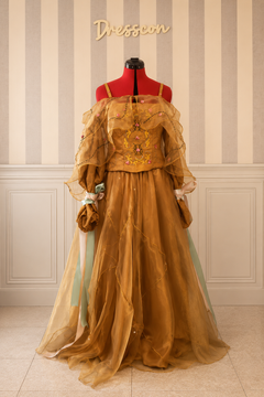 Front view of golden fantasy gown with embroidered corset, sheer organza cape and full layered skirt