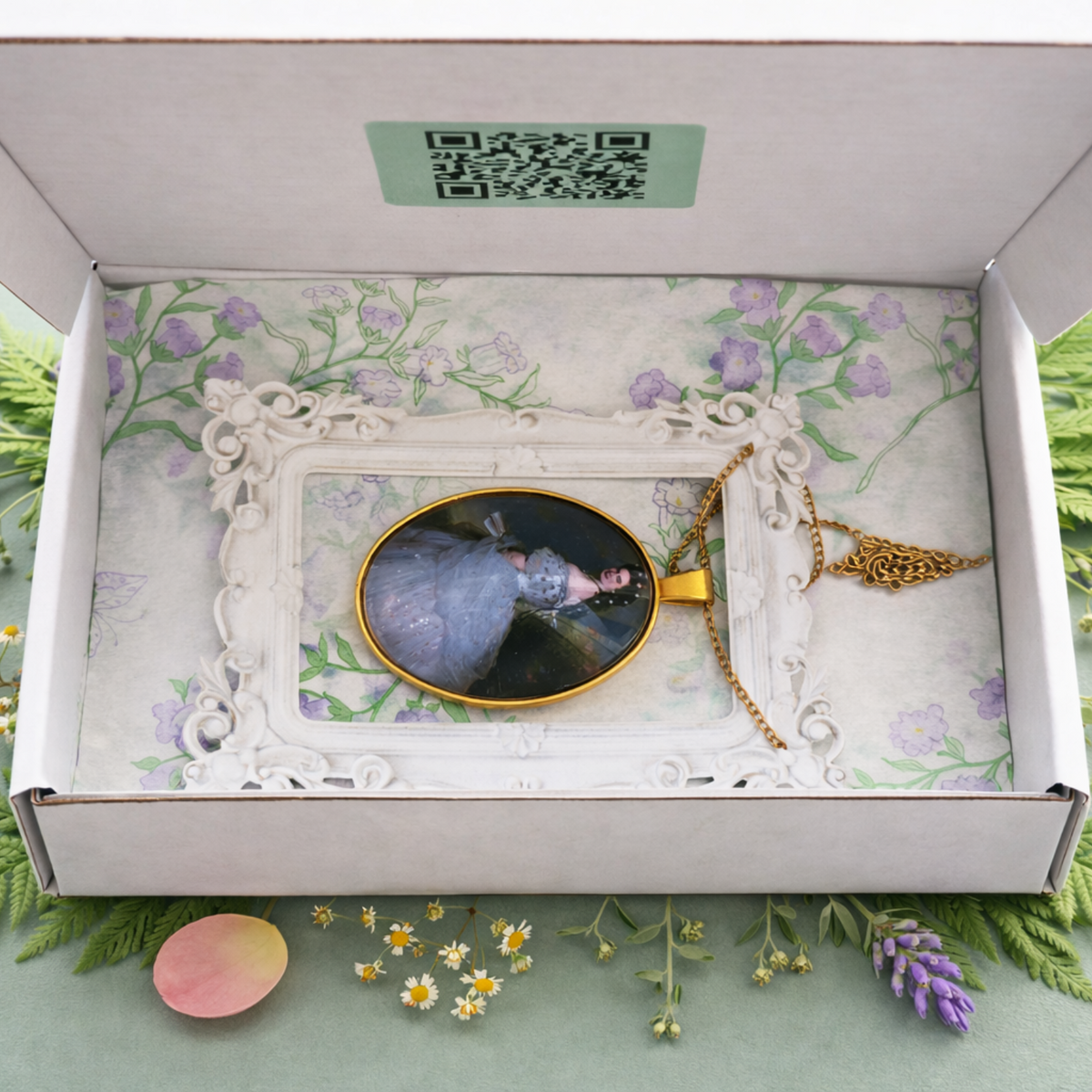 Open DressCon botanical presentation box with an oval glass and brass portrait medallion necklace and matching chain, ready for gifting.